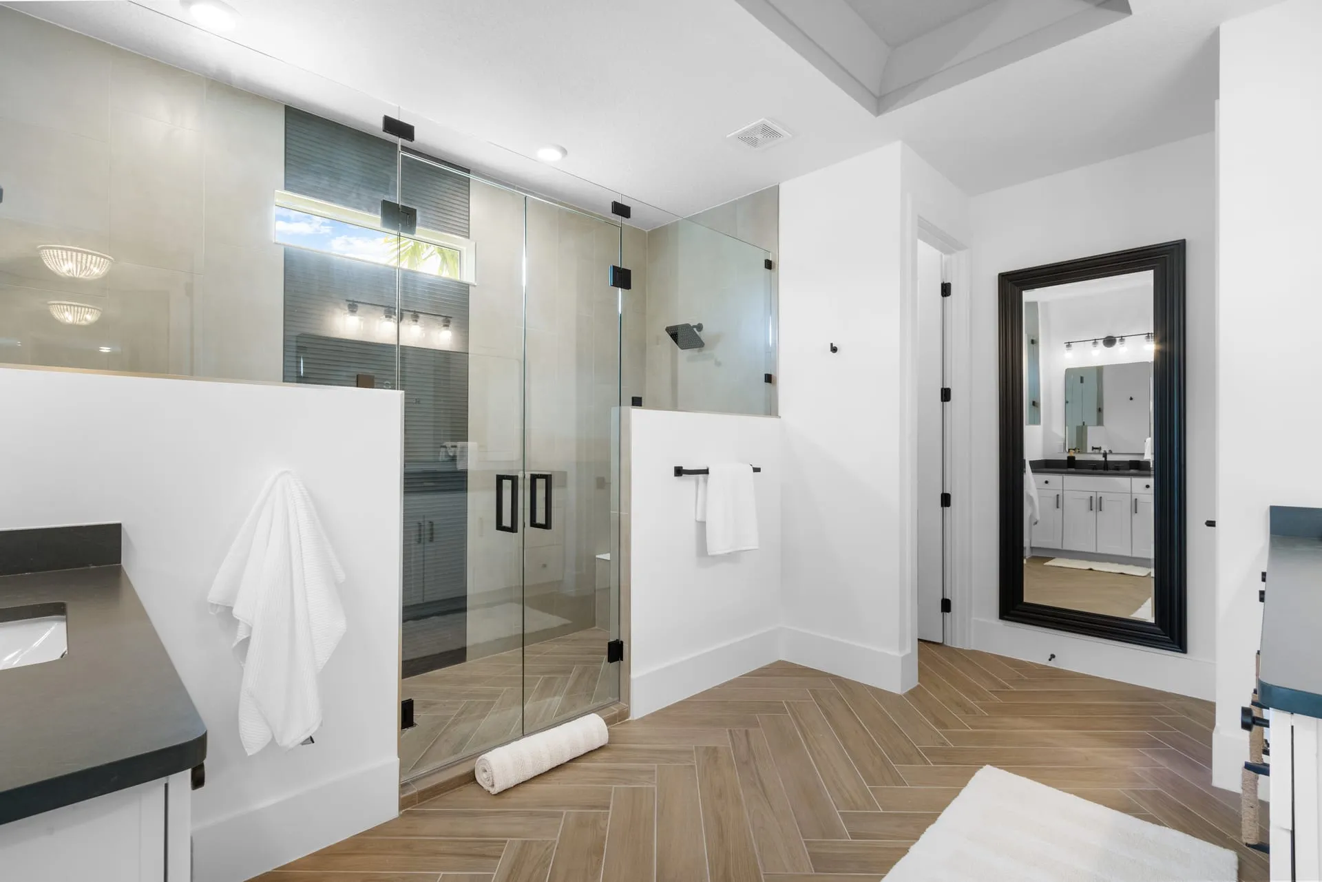 Primary bathroom with a glass walk-in shower and a herringbone wood-look tile floor