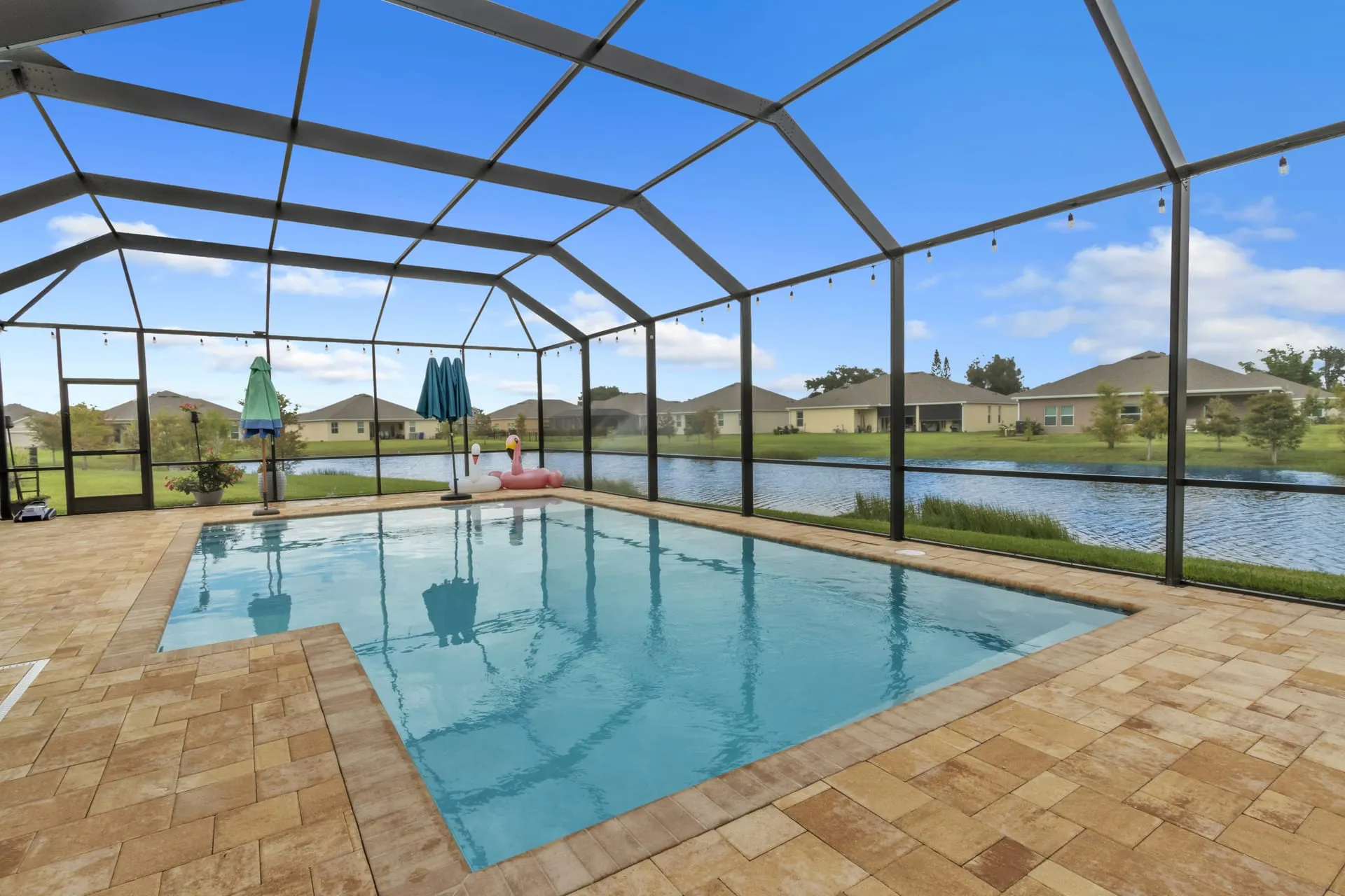 Screened lanai with a pool overlooking a lake and neighborhood homes